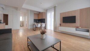 Een moderne woonkamer met een bank, een salontafel en een aan de muur bevestigde televisie.