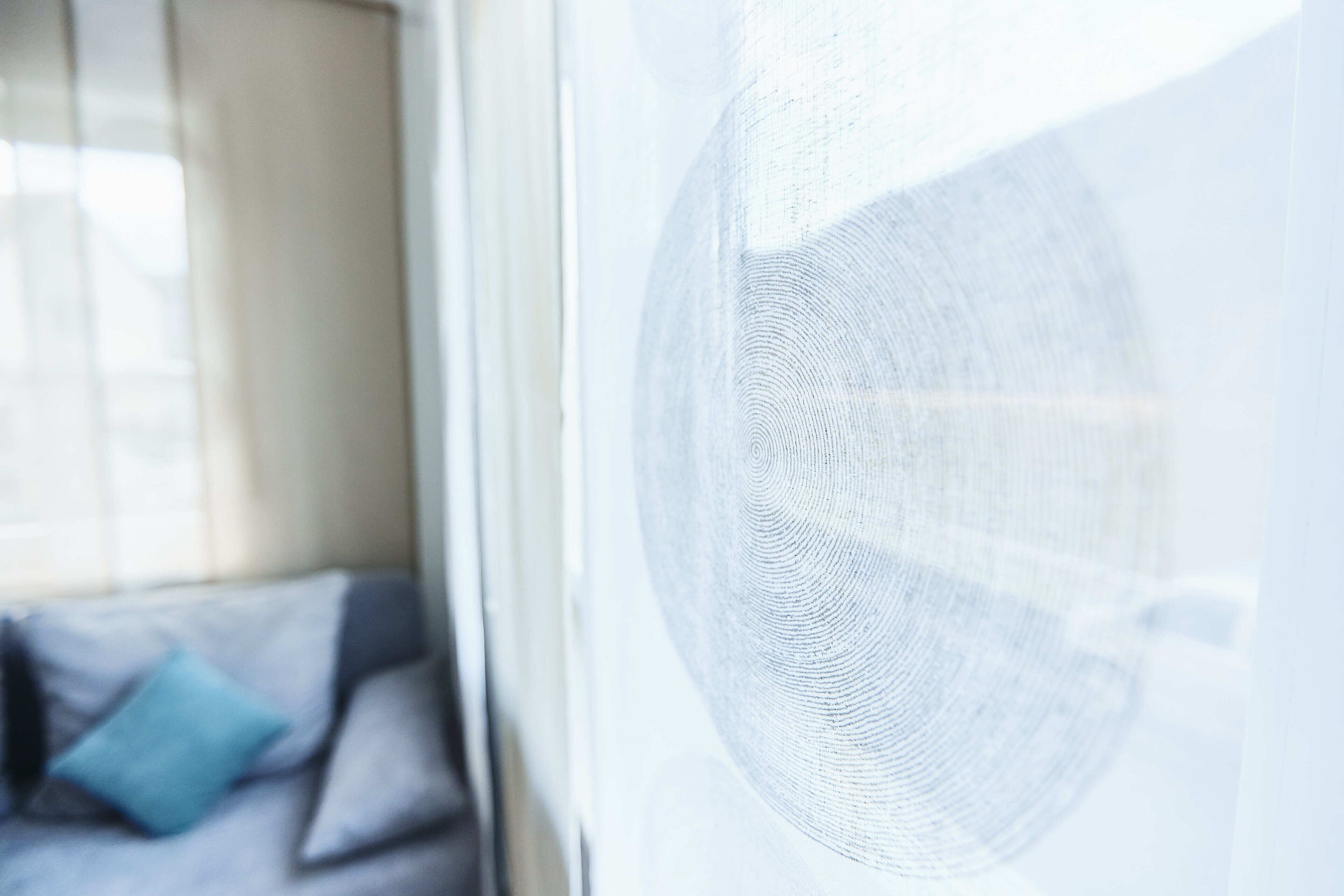 A blurred view of a room with a window, a sofa, and a patterned wall.