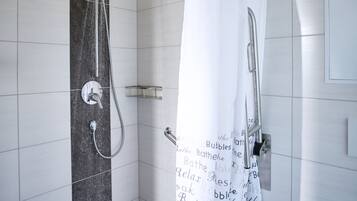Ein modernes Badezimmer mit Dusche, einem weißen Vorhang mit Schriftzug und Fliesenwänden.