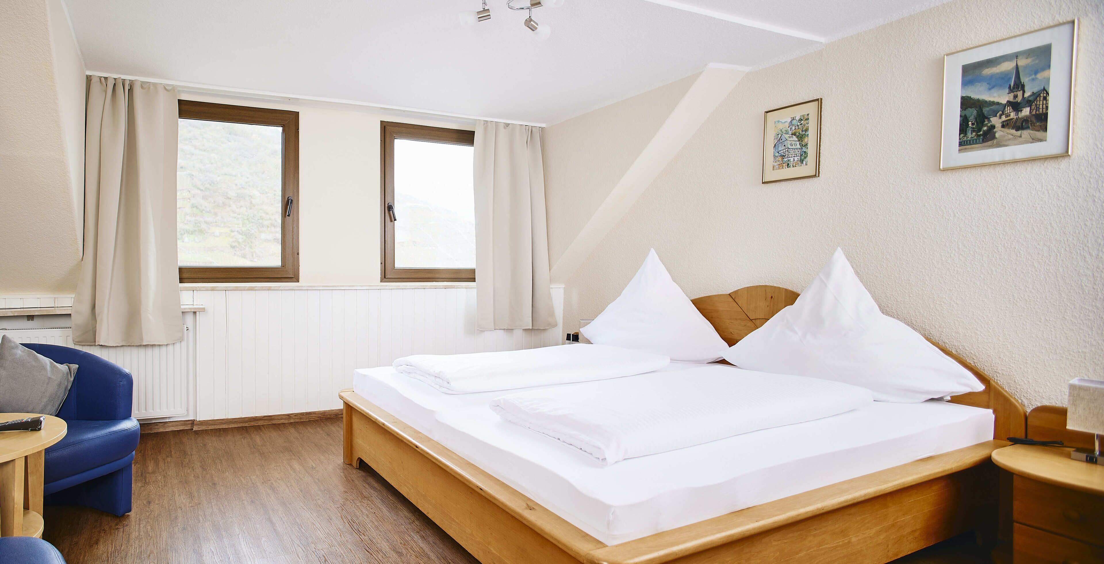 A neatly arranged hotel room with a wooden bed, a blue sofa, and a small table.