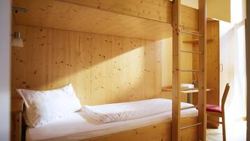 A bunk bed with a ladder, a desk, and a chair in a wooden room.