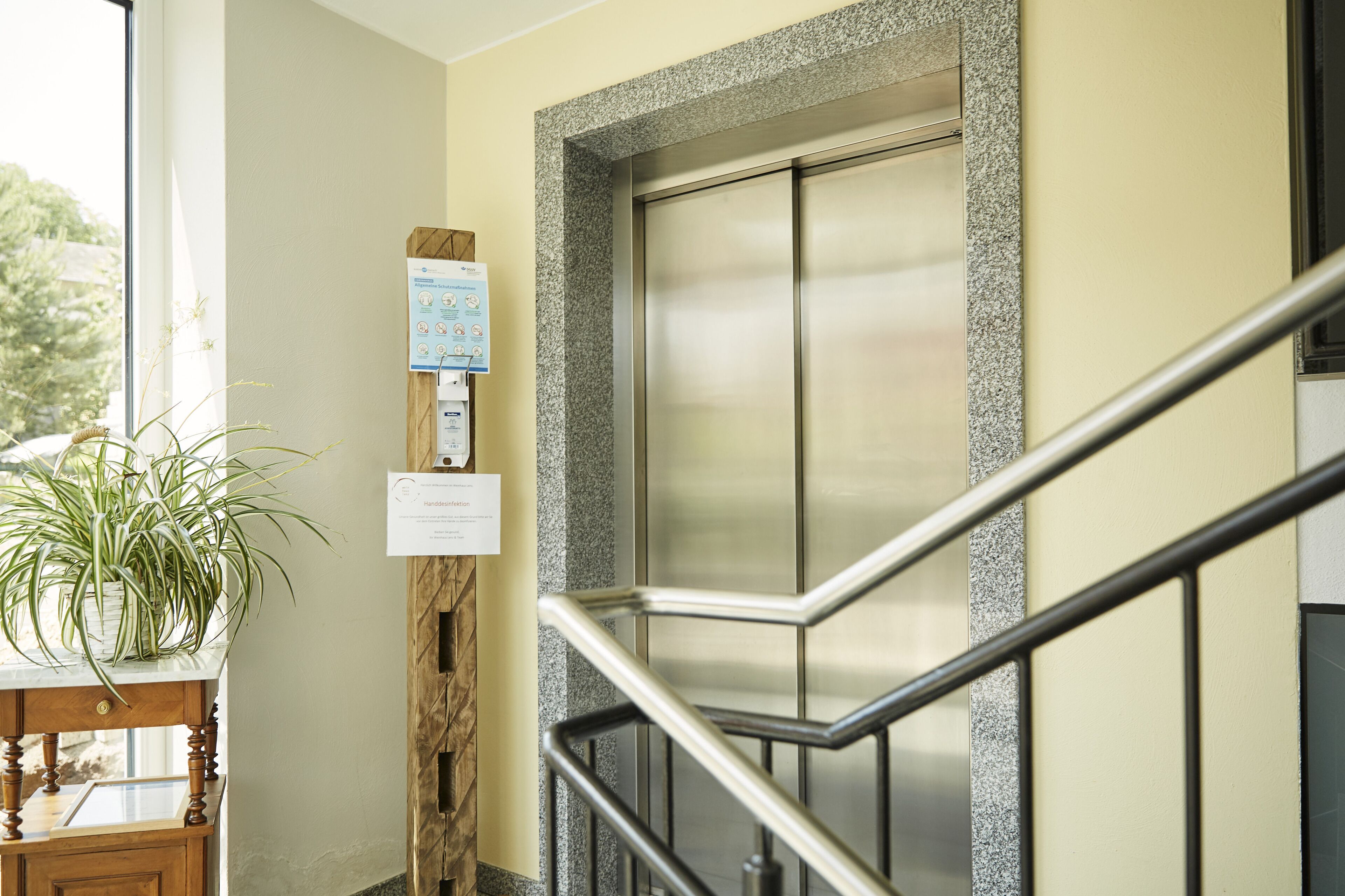 Um elevador de hotel com guarda-corrimão metálico e painel de madeira na parede.