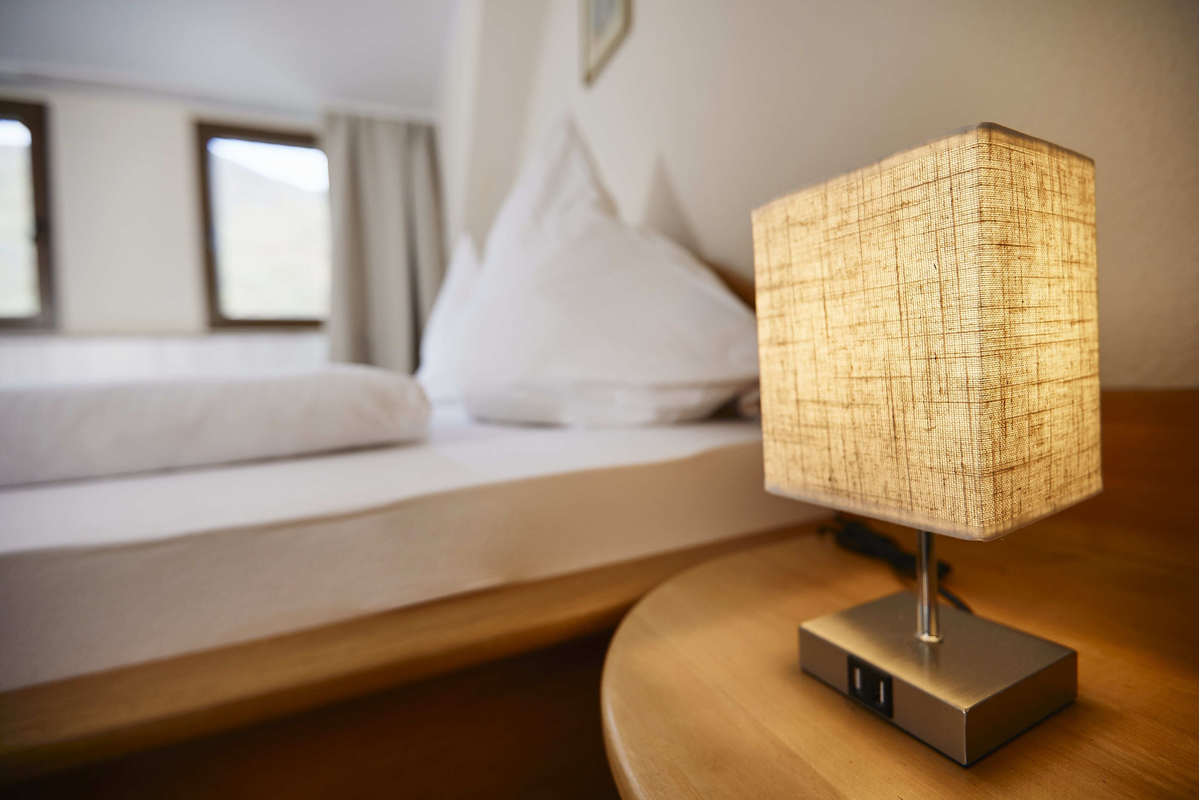 Une chambre d’hôtel moderne avec un lit bien fait, une lampe de chevet et une vue sur l’extérieur par la fenêtre.