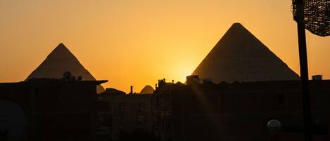 Deux pyramides se découpent sur le ciel au coucher du soleil.