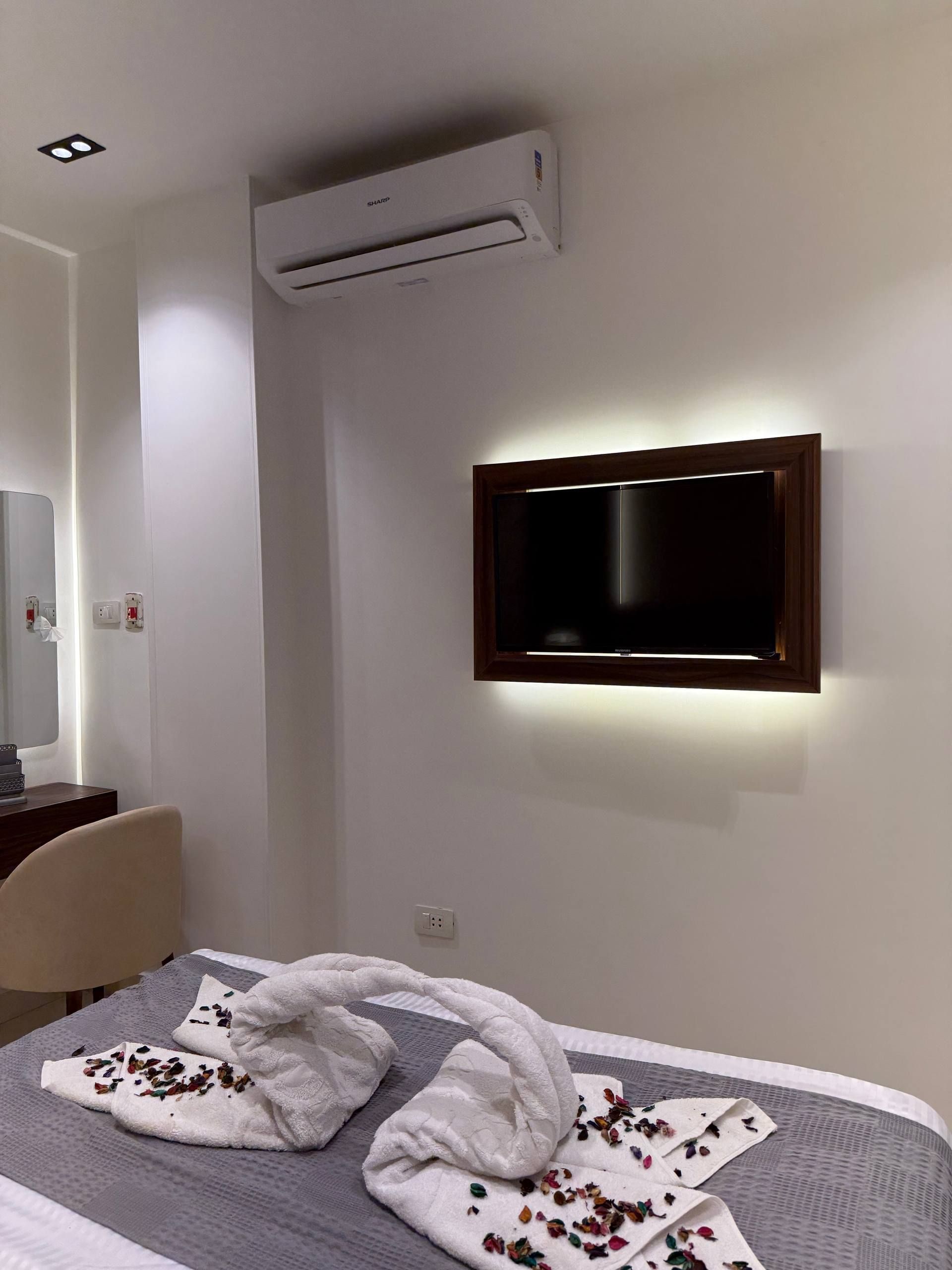 Habitación de hotel con cama, televisor montado en la pared, aire acondicionado y escritorio con silla.