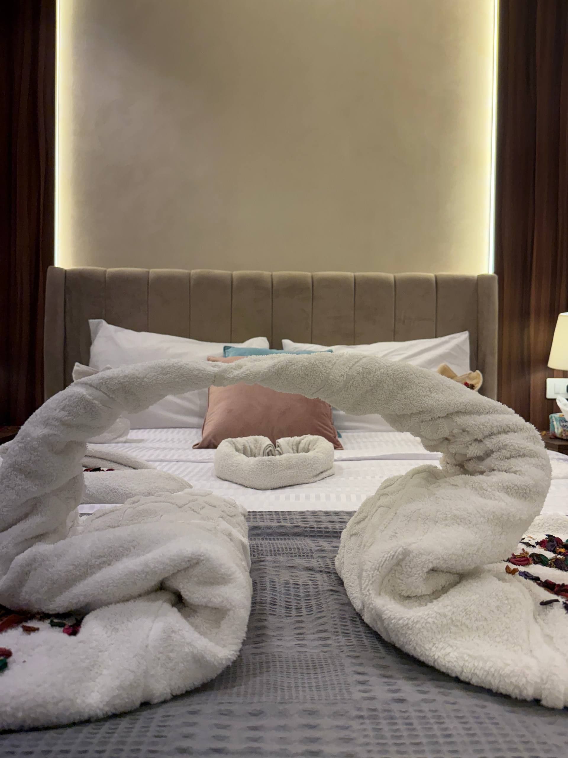 A hotel room with a bed, a headboard, a bedside table, and a lamp.