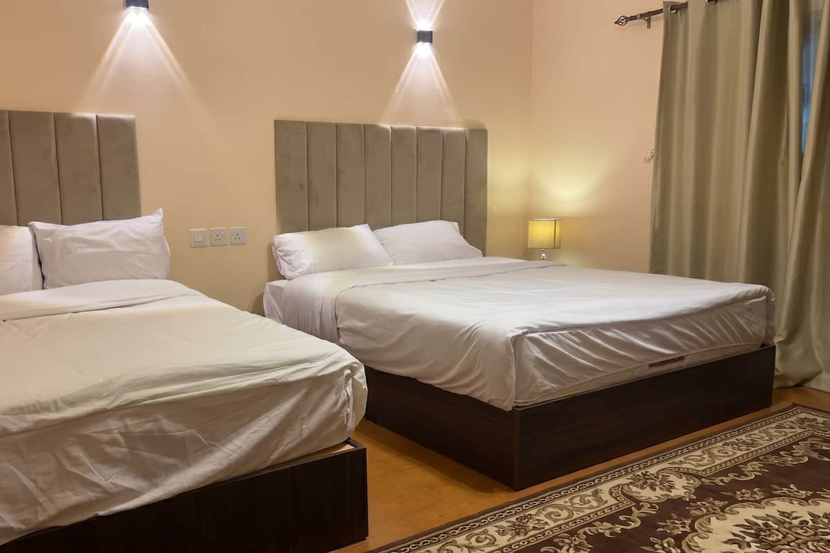 Two twin beds with headboards, a bedside lamp, and a patterned rug.