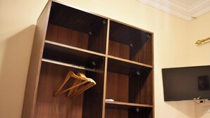 A wooden wardrobe with multiple compartments, a hanging rod, and a mounted television.