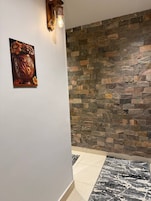 Un pasillo con pared de piedra, una obra de arte enmarcada y una alfombra estampada.
