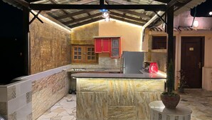 A kitchen with a marble countertop, a sink, cabinets, and a refrigerator.