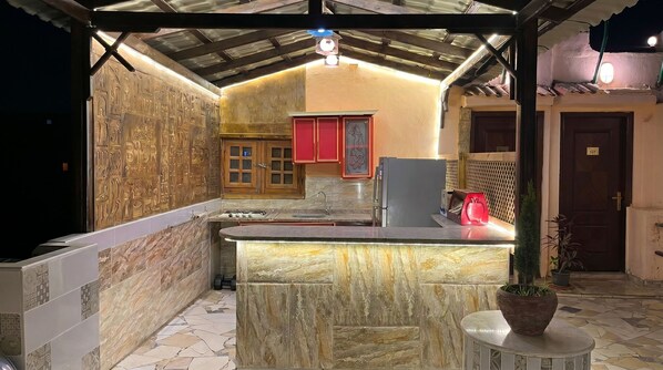 A kitchen with a marble countertop, a sink, cabinets, and a refrigerator.