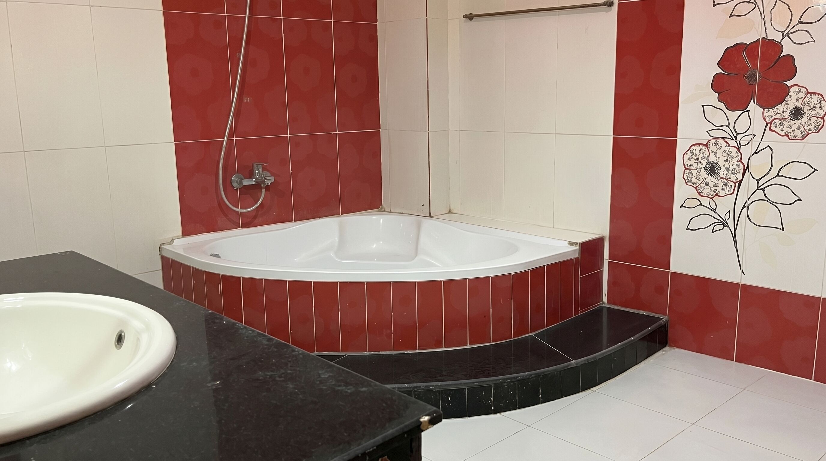 Une salle de bain avec une baignoire blanche, un lavabo et des murs recouverts de carreaux rouges et blancs.