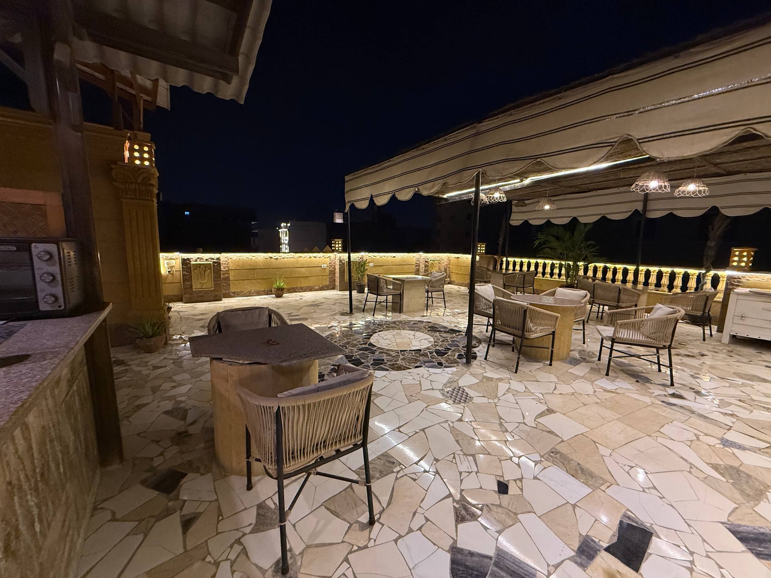 An outdoor patio area with stone flooring, outdoor seating, and ambient lighting.