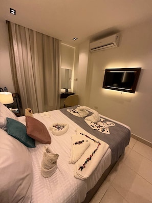 Una habitación de hotel con una cama, un televisor montado en la pared y un equipo de aire acondicionado.