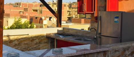 Cocina compacta con estufa a gas, pileta y refrigerador de acero inoxidable.
