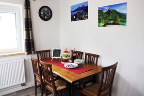 A dining area with a table set for four, featuring a bowl of grapes and a glass of water.