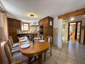 Ett rymligt kök med träskåp, ett matbord med plats för fyra personer och en modern taklampa.