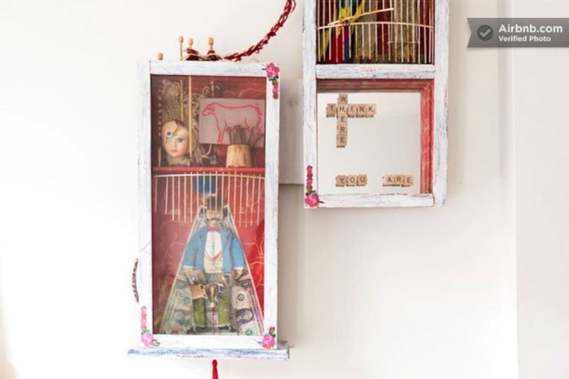 Two wall-mounted decorations with various items and text, including a framed picture and a cage with toys.