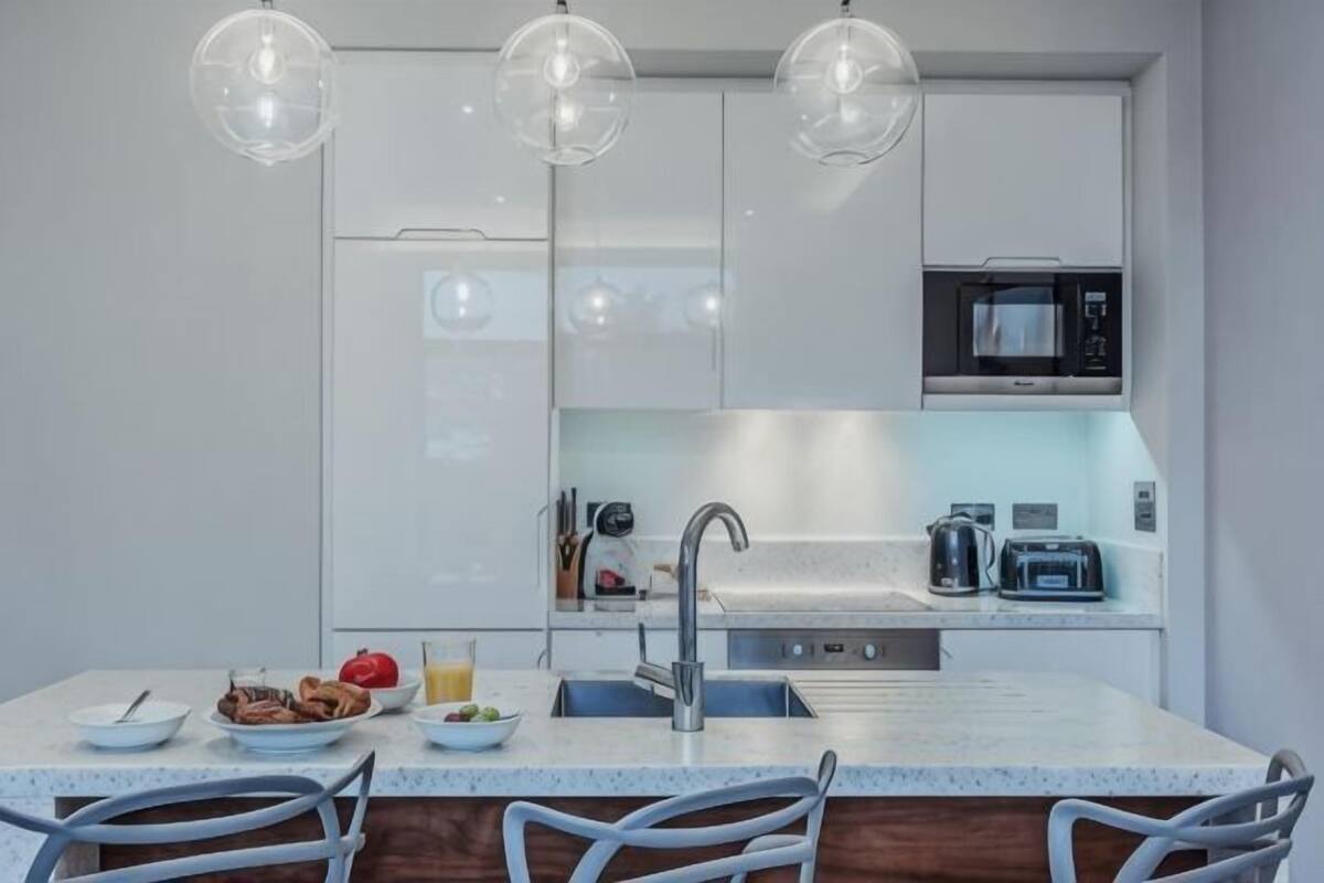 A modern kitchen with a central island, stainless steel appliances, and pendant lighting.