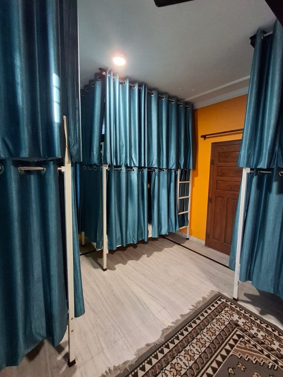 Una habitación con piso de madera, un tapete estampado y una puerta de madera.