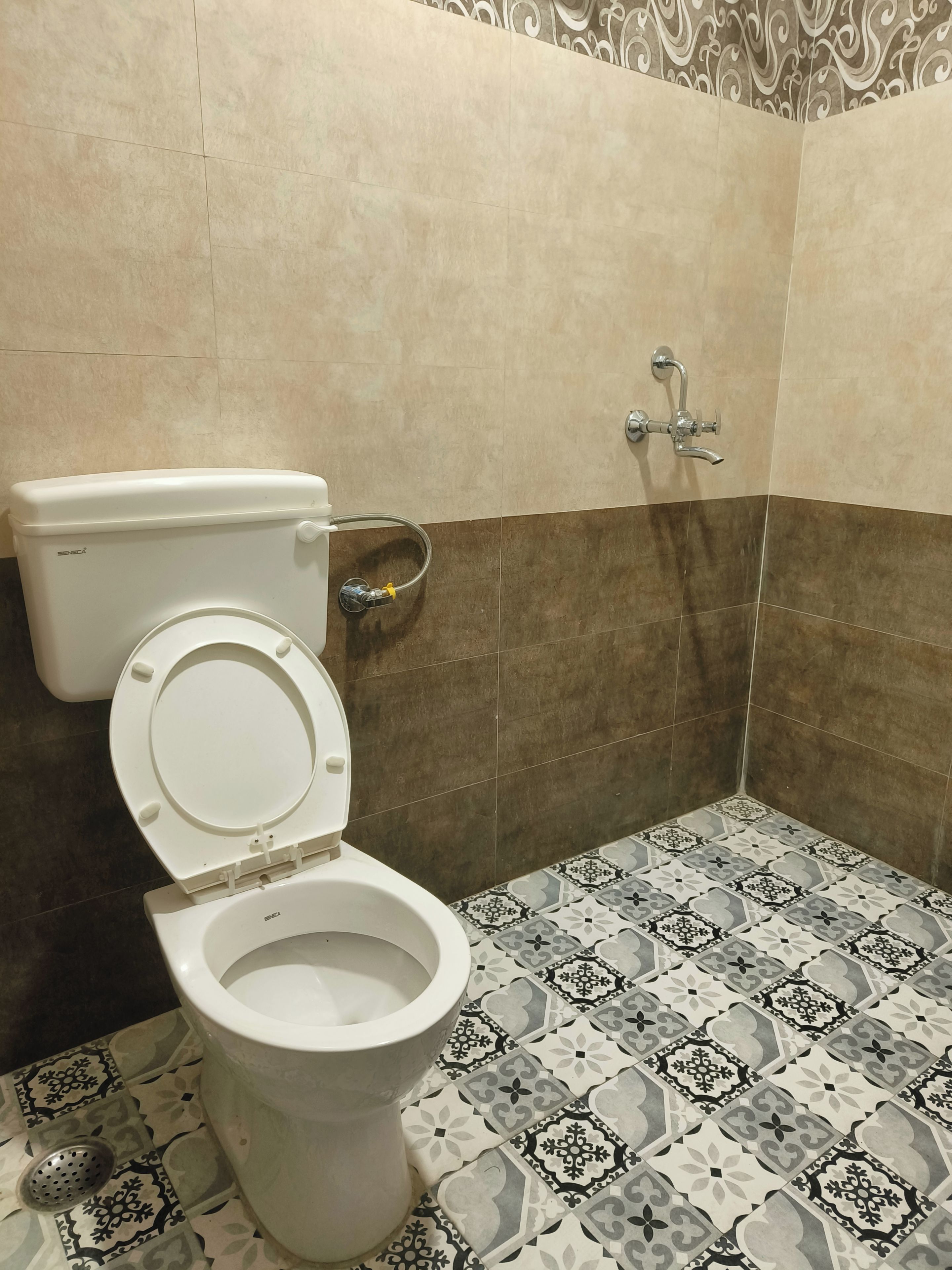 Un baño con inodoro, ducha y azulejos con diseño.