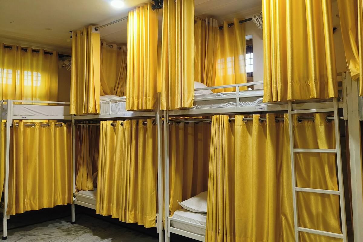 Une chambre de dortoir avec des lits superposés, des rideaux jaunes et un ventilateur de plafond.