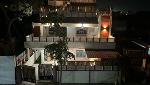 A multi-story building with a balcony and a lit entrance.