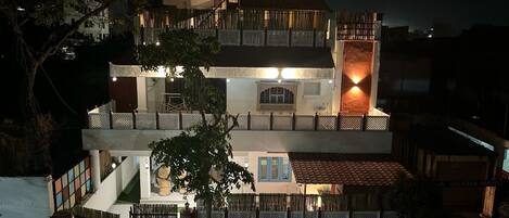 A multi-story building with a balcony and a lit entrance.