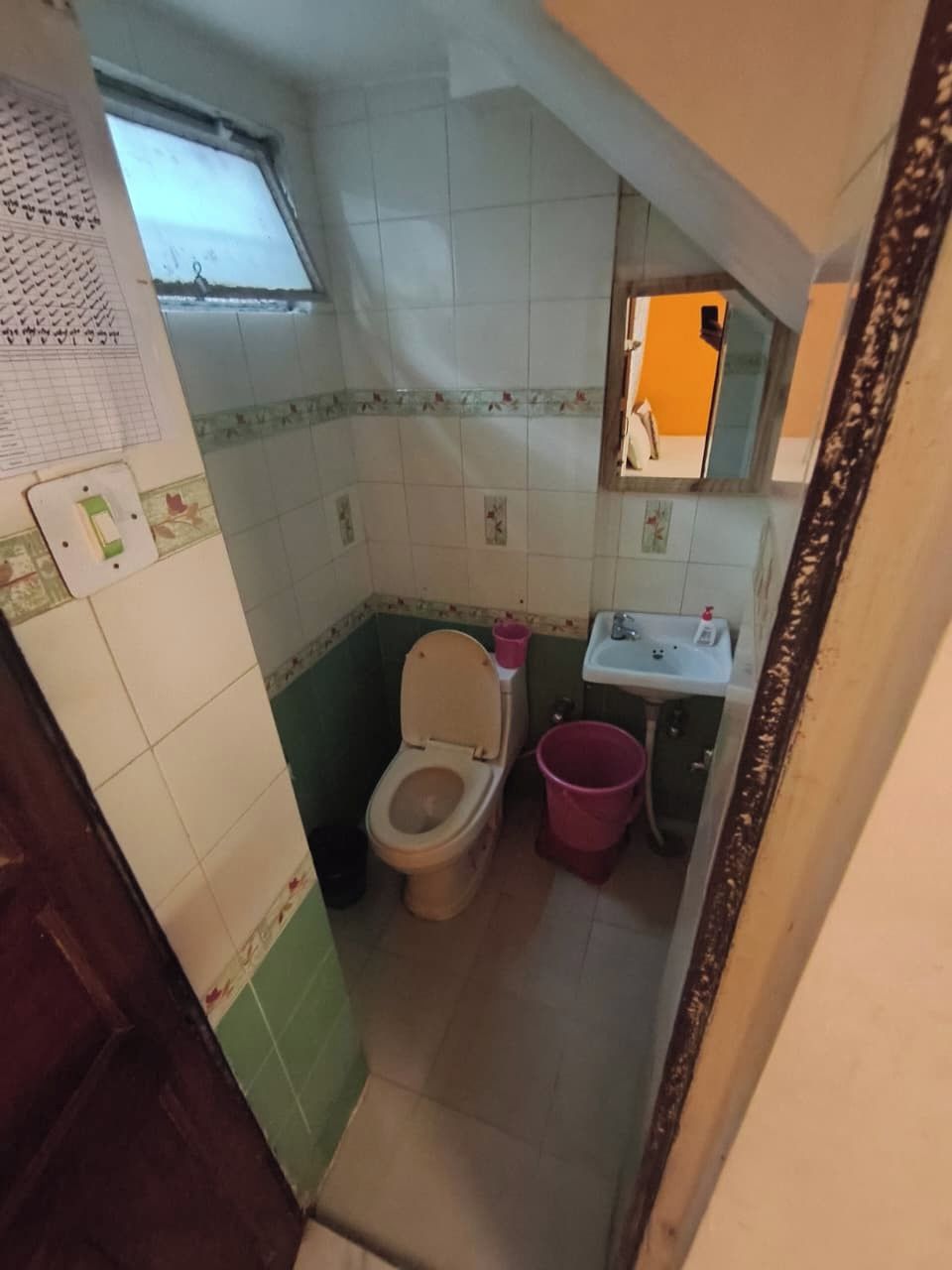 A small bathroom with a toilet, sink, and a window.