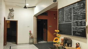 A hallway with a ceiling fan, a cat on the wall, a chalkboard menu, and a table with decorative items.