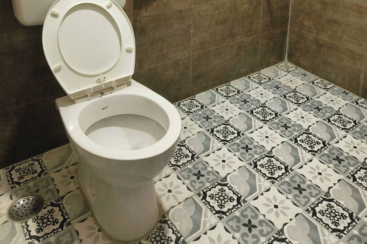 Une salle de bain avec des toilettes, une douche et des carreaux décorés.