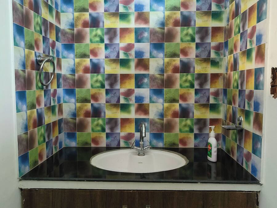 Un baño con salpicadero de azulejos de mosaico de colores, un lavabo blanco y un mueble de madera oscura.