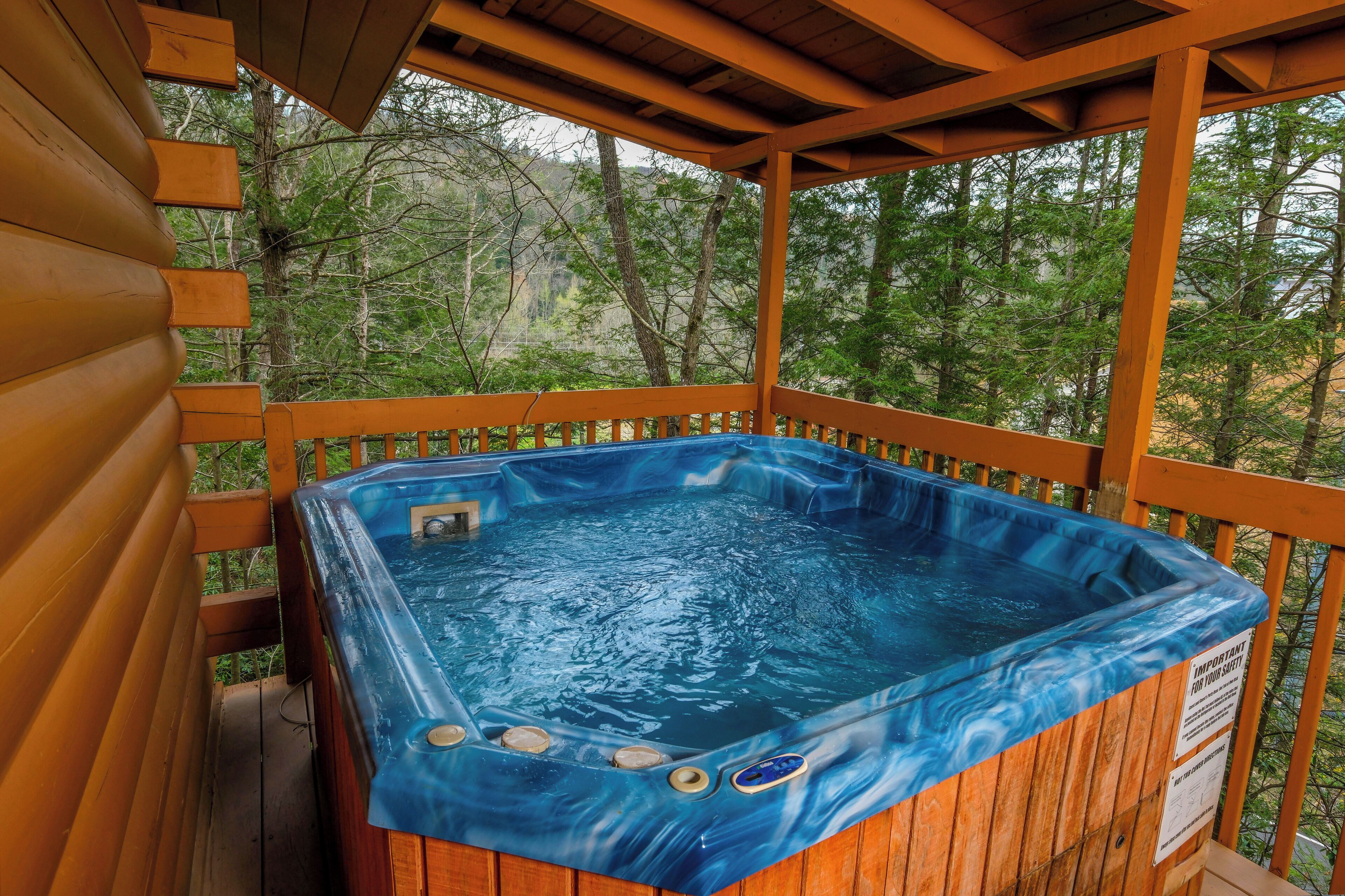Een hottub op een houten terras met uitzicht op bomen.