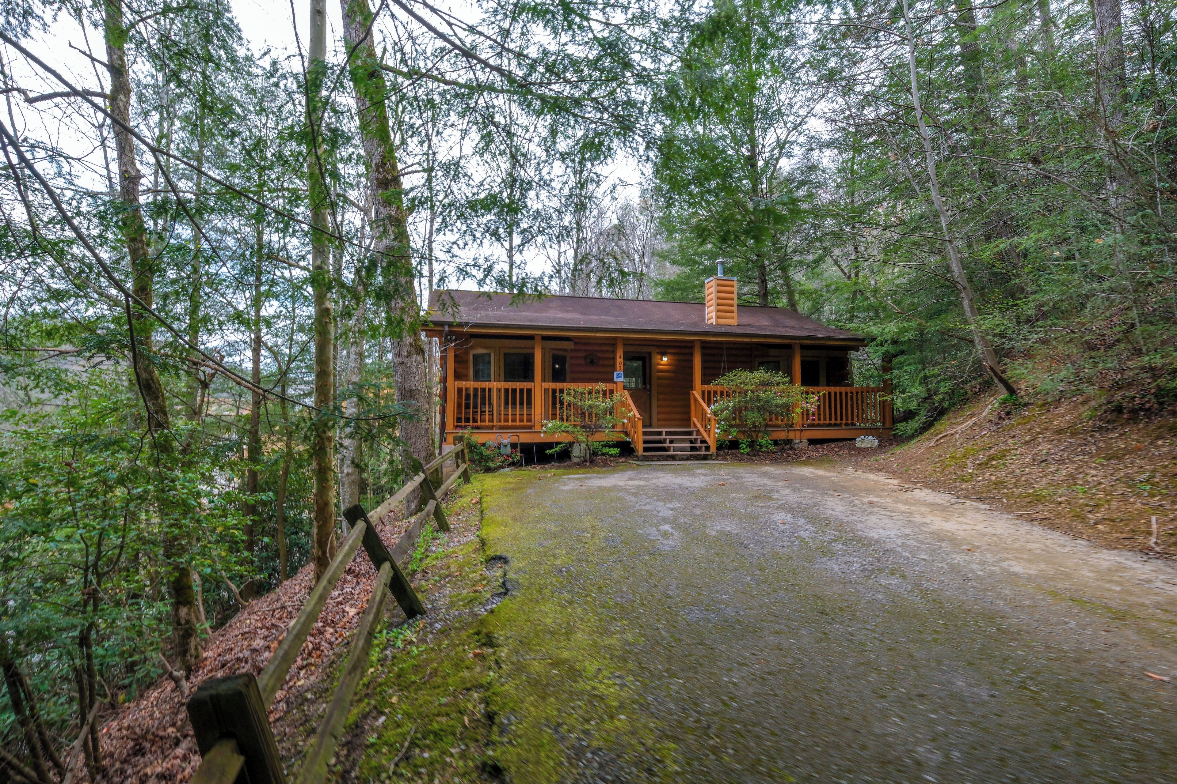 A cabin with a wooden deck, surrounded by dense forest.
