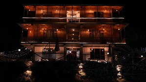 Um edifício com várias andares, varandas e áreas de estar ao ar livre, iluminado à noite.