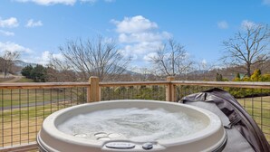 A hot tub on a deck with a view of a fenced yard and mountains in the background. - Cozy 3 Bedroom with King Beds, Mountain View, Game Room, WiFi, Hot Tub, Fire Pit (Sevierville)