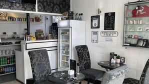 Una cafetería con mostrador, sillas, refrigerador y una pizarra de menú.