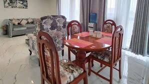 Un comedor con una mesa redonda y cuatro sillas, un sofá y una araña.
