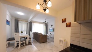 Una sala de estar moderna con comedor, sofá, televisor y dispensador de agua.