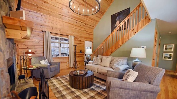 A cozy log cabin interior with a checkered floor, a staircase, and a sofa set. - Hayden’s Hideaway - View, hot tub, game room, fun! (Blairsville)