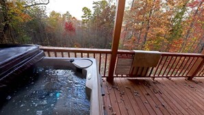 A hot tub on a wooden deck with a view of autumn trees. - Hayden’s Hideaway - View, hot tub, game room, fun! (Blairsville)