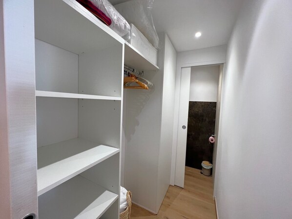 A hallway with a white closet, a wooden floor, and a door leading to a bathroom.