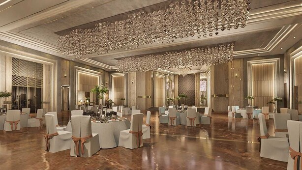 A spacious banquet hall with round tables and chairs, a large ornate chandelier, and a polished wooden floor. - Jacaranda Heights (Islamabad)
