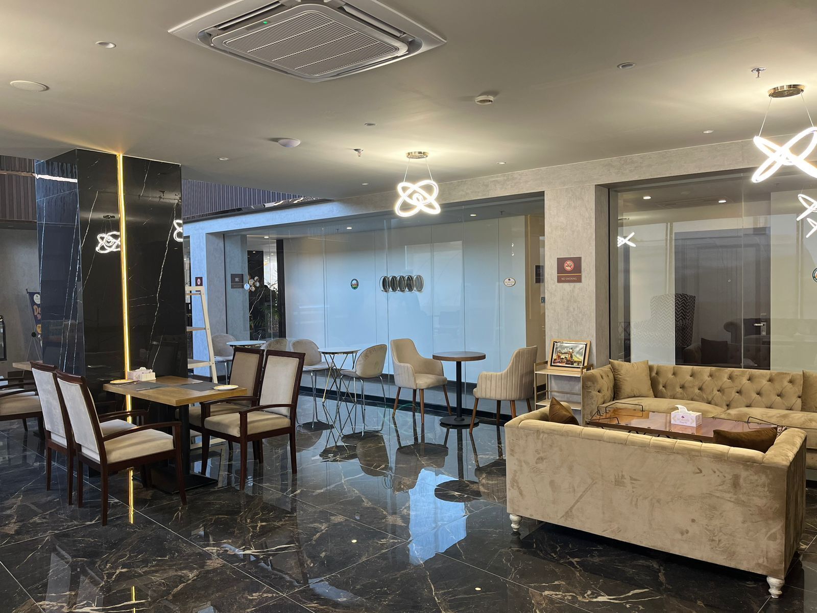 A modern lobby with a marble floor, a sofa, and a dining area with chairs and tables.