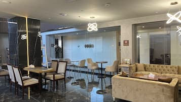 Eine moderne Lobby mit Marmorboden, einer Couch und einem Essbereich mit Stühlen und Tischen.
