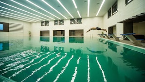 An indoor swimming pool with a diving board and multiple windows. - Jacaranda Heights (Islamabad)