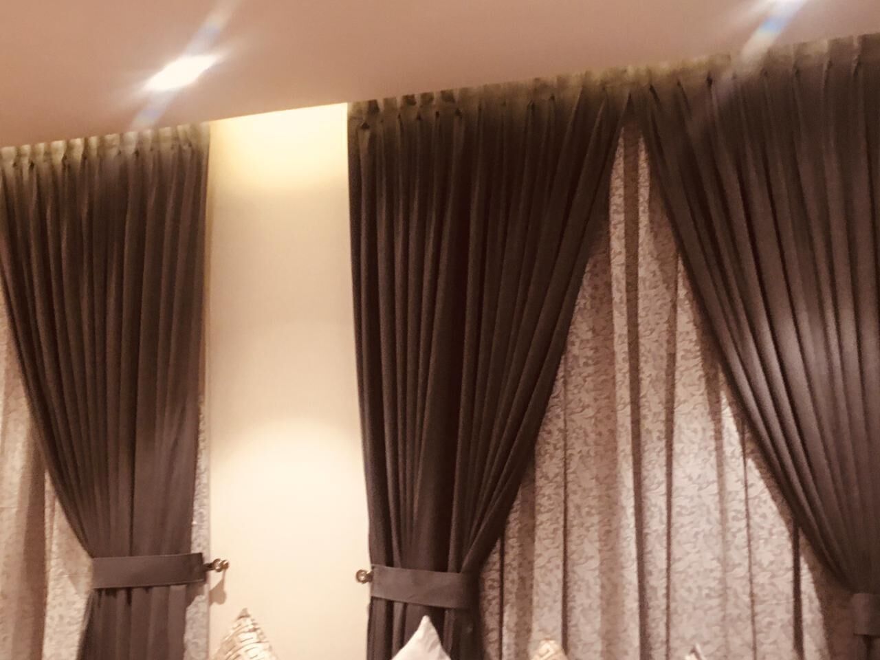 A room with dark curtains and a light fixture on the ceiling.