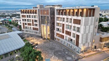 Un hotel moderno con un patio central, varios pisos y fachadas de vidrio y ladrillo.