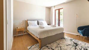 Een slaapkamer met een bed, nachtkastje en vloerlamp.