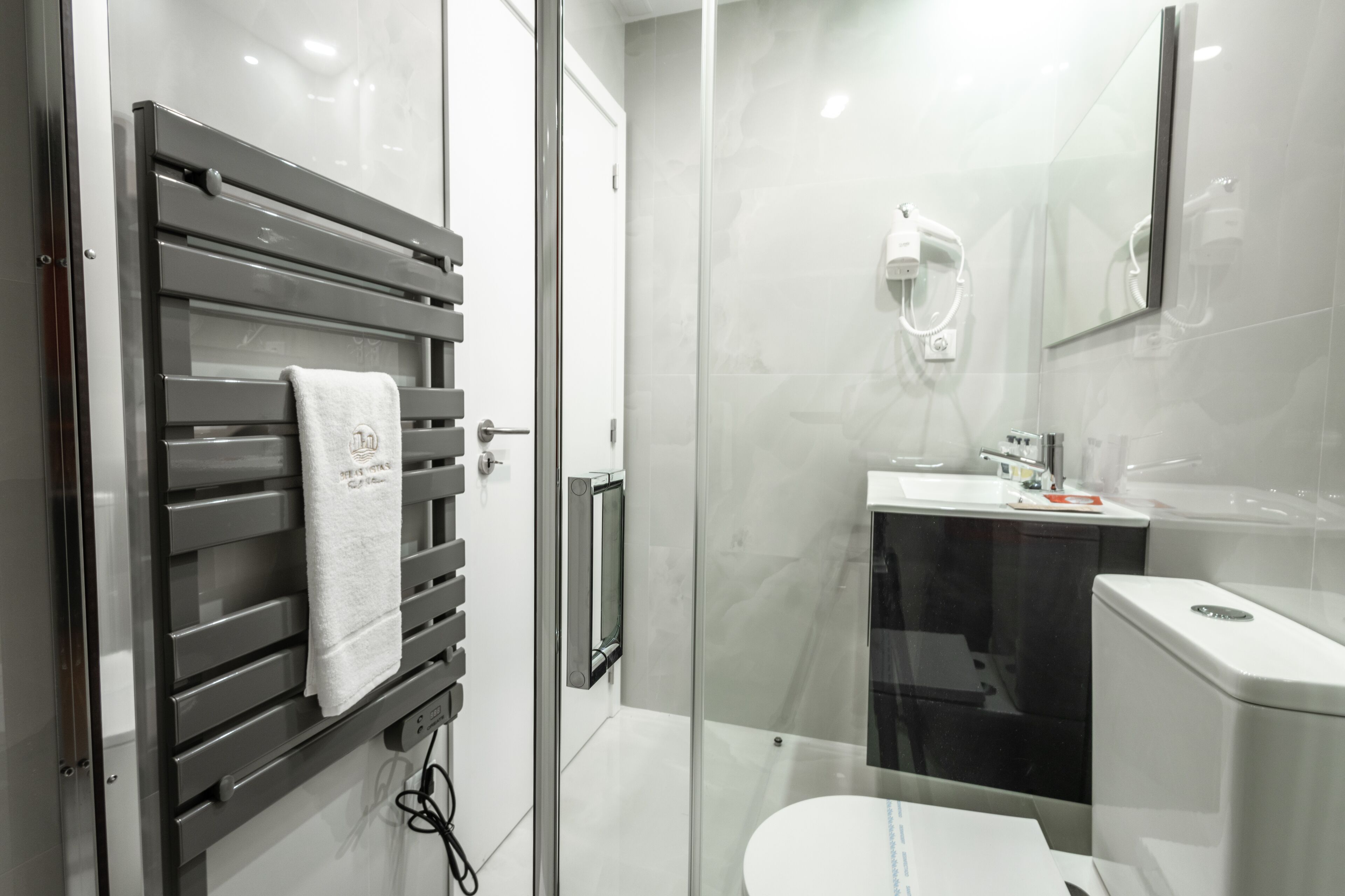 Un bagno moderno con box doccia in vetro, un water e un lavandino.